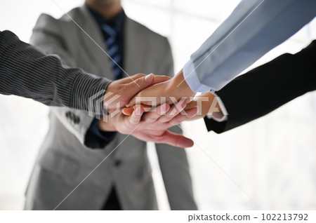 Top view of diverse businesspeople putting their hands together during the meeting. Top view of diverse businesspeople putting their hands together during the meeting. 102213792