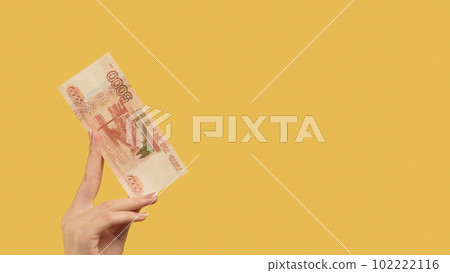 Bank deposit. Mortgage payment. Female hand holding rubles showing 5000 cash on yellow background copy space. 102222116