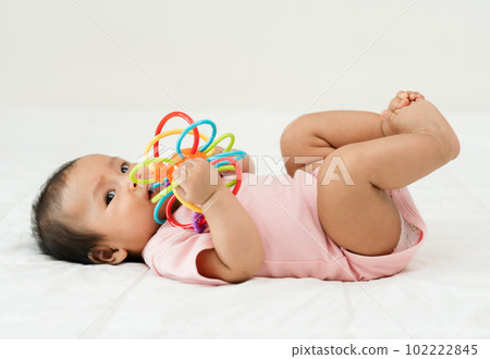 infant baby biting colorful rubber bites toy on bed 102222845