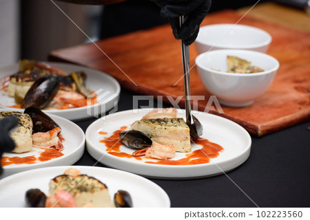chef in the restaurant prepares saganaki, traditional Greek cheese snack that is fried in a pan or grilled 102223560