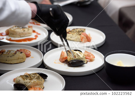 chef in the restaurant prepares saganaki, traditional Greek cheese snack that is fried in a pan or grilled 102223562
