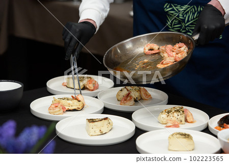 chef in the restaurant prepares saganaki, traditional Greek cheese snack that is fried in a pan or grilled 102223565