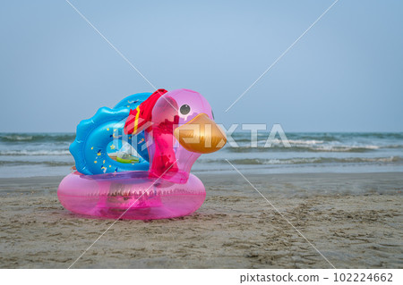 Inflatable duck on a sandy beach. Sea and blue sky at the background. Inflatable duck on a sandy beach. Sea and blue sky at the background. 102224662