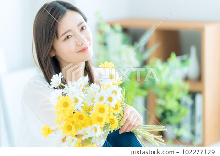 在客廳裡拿著花束的年輕女人 102227129