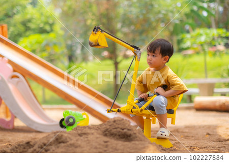Kid baby boy todler playing construction truck toy diging sand in playground 102227884