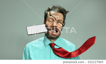 Expressive sad man, businessman in tie taking punch in face by flying smart phone. Concept of personal problems, financial loses, business fall 102227905