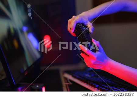 Female cyber hacker gamer use joystick to competition and playing games on computer in neon light Female cyber hacker gamer use joystick to competition and playing games on computer in neon light 102228327