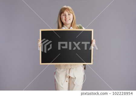 smiling teenager girl in beige tracksuit showing blank board smiling teenager girl in beige tracksuit showing blank board 102228954