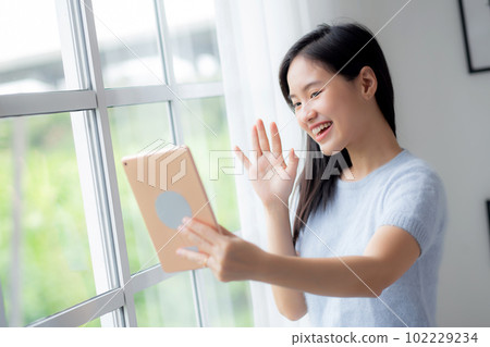 Happiness young asian woman video call with digital tablet in the living room at home. Happiness young asian woman video call with digital tablet in the living room at home. 102229234