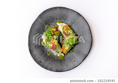 Spring roll on a black plate isolated Spring roll on a black plate isolated 102229545