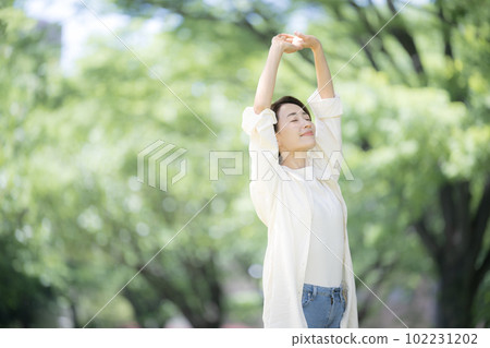 A beautiful woman taking a deep breath in the fresh greenery, relaxing and stretching, a stress-free image Copy space on the left A beautiful woman taking a deep breath in the fresh greenery, relaxing and stretching, a stress-free image Copy space on the left 102231202