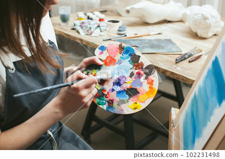 The artist with a palette and a brush in her hands. Close-up. The artist with a palette and a brush in her hands. Close-up. 102231498