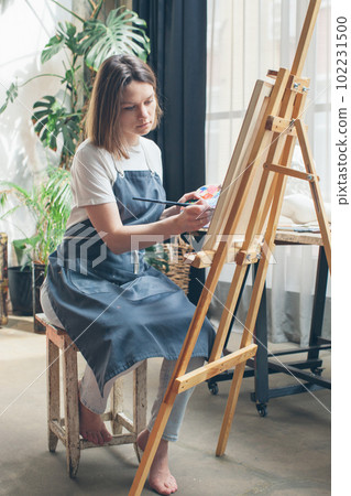 The artist paints at the easel. The artist paints at the easel. 102231500