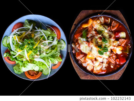 Stewed beef with cheese and vegetables on wooden plate isolated on black background top view Stewed beef with cheese and vegetables on wooden plate isolated on black background top view 102232143