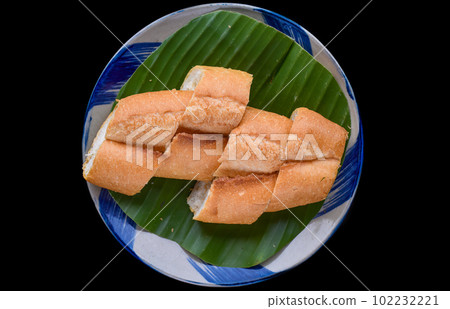 Sliced Vietnamese traditional Banh Mi baguette on black background 102232221