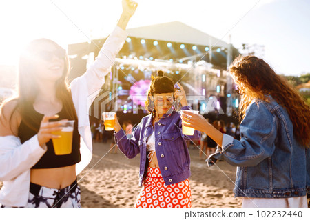 Girlfriends drinking beer, having fun at music festival. Friendship and celebration. Summer holiday. 102232440