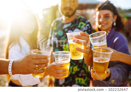 Young happy friends drinking beer and having fun at music festival together. Friendship. 102232647