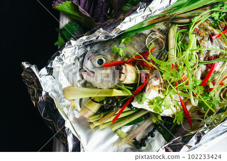 Pampus argenteus fish grilled in Vietnamese style with vegetables isolated on black background top view Pampus argenteus fish grilled in Vietnamese style with vegetables isolated on black background top view 102233424