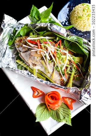 Pampus argenteus fish grilled in Vietnamese style with vegetables isolated on black background top view Pampus argenteus fish grilled in Vietnamese style with vegetables isolated on black background top view 102233435