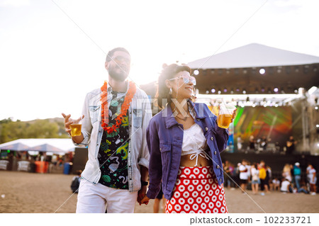 Young and cheerful couple at music festival. Happy friends drinking beer and having fun. Young and cheerful couple at music festival. Happy friends drinking beer and having fun. 102233721