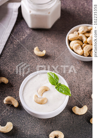 Fresh cashew sauce with basil in a bowl for a vegetarian diet vertical view Fresh cashew sauce with basil in a bowl for a vegetarian diet vertical view 102235358