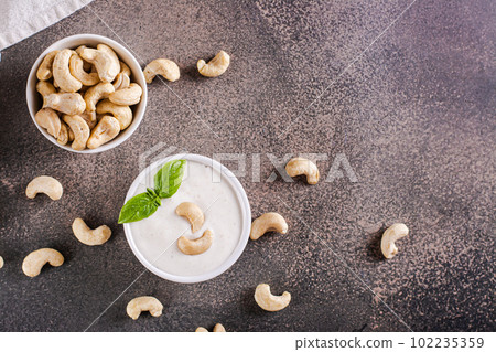 Vegan cashew sauce in bowl with basil on table for plant based diet top view Vegan cashew sauce in bowl with basil on table for plant based diet top view 102235359