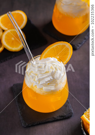Dirty orange soda with whipped cream in glasses and orange slices on the table vertical view Dirty orange soda with whipped cream in glasses and orange slices on the table vertical view 102235366