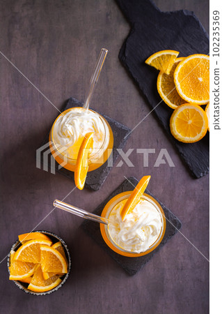 Dirty orange soda with whipped cream in glasses and orange slices on the table top and vertical view Dirty orange soda with whipped cream in glasses and orange slices on the table top and vertical view 102235369