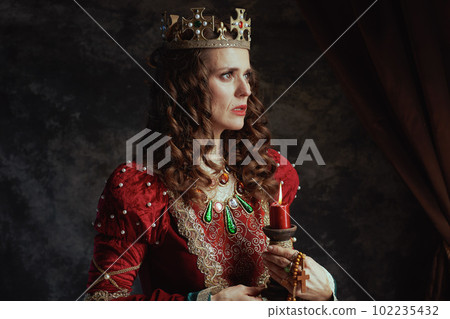 medieval queen in red dress with candle and crown 102235432