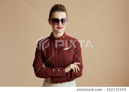 stylish air hostess woman on beige background with sunglasses 102235543