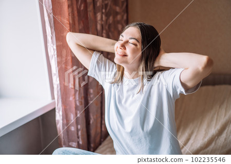 Happy lady in white t-shirt sitting on bed Happy lady in white t-shirt sitting on bed 102235546