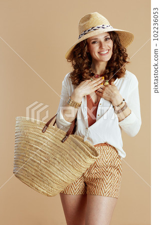 smiling housewife in blouse and shorts on beige smiling housewife in blouse and shorts on beige 102236053