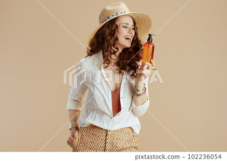 smiling stylish female in blouse and shorts isolated on beige smiling stylish female in blouse and shorts isolated on beige 102236054