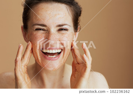 Portrait of smiling modern woman with face scrub 102236162