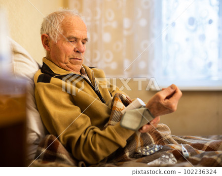Elderly Senor measuring pressure with tonometer at Home 102236324
