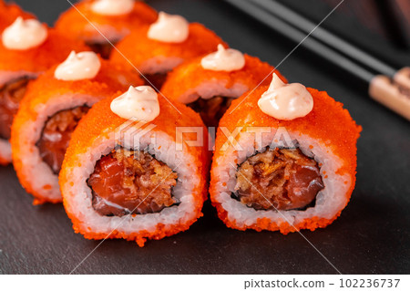 Sushi roll with tuna, onion in batter and tobiko caviar served on black board close-up - Japanese food Sushi roll with tuna, onion in batter and tobiko caviar served on black board close-up - Japanese food 102236737