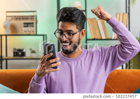 Indian man use smartphone celebrating winning, lottery jackpot goal achievemen, good news, victory 102237457