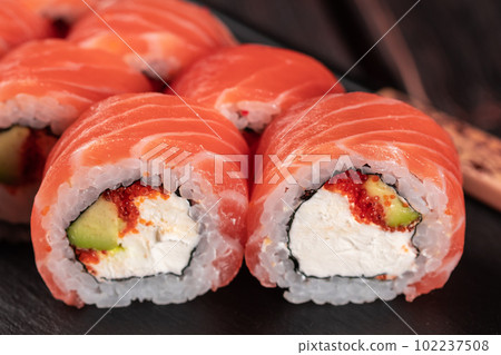Sushi roll maguro with salmon avocado and tobiko, philadelphia cheese on black board close-up. Sushi menu. Japanese food. Sushi roll maguro with salmon avocado and tobiko, philadelphia cheese on black board close-up. Sushi menu. Japanese food. 102237508