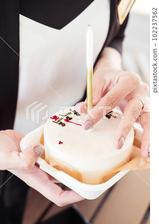Bento cake with a candle with a girl's hand,close-up.Little surprise for a girl's birthday Bento cake with a candle with a girl's hand,close-up.Little surprise for a girl's birthday 102237562