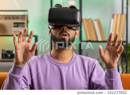 Man using virtual reality futuristic technology headset to play simulation 3D video game at home Man using virtual reality futuristic technology headset to play simulation 3D video game at home 102237602
