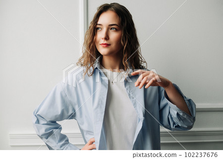 A pensive woman in blue shirt reminiscing about past love, smiling yet with a touch of sadness 102237676