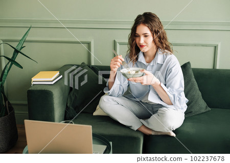 Relaxing weekend at home: Young woman in cozy clothes binge-watching TV series, enjoying leisure Relaxing weekend at home: Young woman in cozy clothes binge-watching TV series, enjoying leisure 102237678