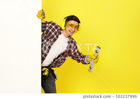 smiling professional builder in work clothes in helmet with level . smiling professional builder in work clothes in helmet with level . 102237999
