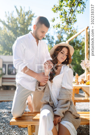 Beautiful wedding couple laugh and kiss relaxing in rv, camping in a trailer. Romantic moment. 102238337