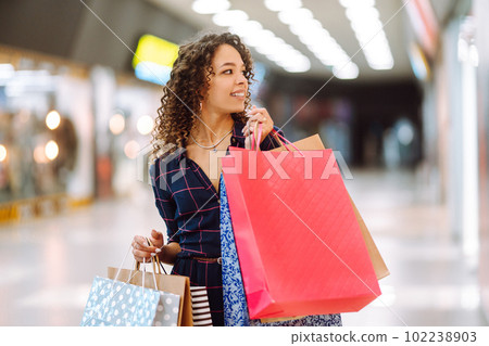 Smiling woman with shopping bags enjoying shopping in the mall.Young woman with packages after shopping. 102238903