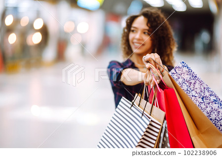 Young woman after shopping with shopping bags walks in the mall. Spring shoopping. Young woman after shopping with shopping bags walks in the mall. Spring shoopping. 102238906