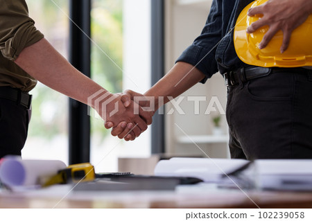 Architect and Engineer working with blueprints for architectural plan, engineer sketching a construction project, green energy concept 102239058