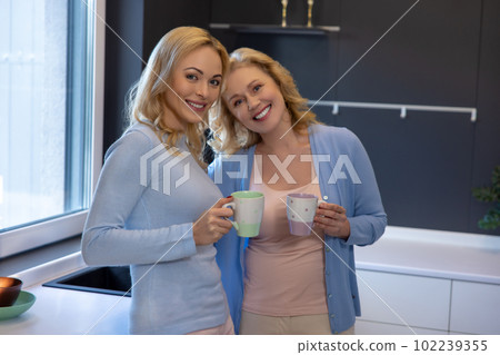 Young female and her parent communicating over coffee at home Young female and her parent communicating over coffee at home 102239355