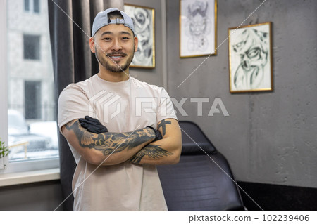 Asian young man standing in the tattoo salon Asian young man standing in the tattoo salon 102239406