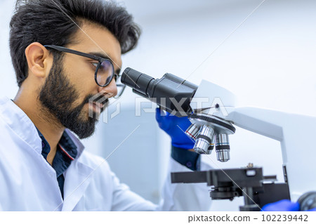 Scientist conducts experiments, adjusts specimen in petri dish and looking on it into microscope Scientist conducts experiments, adjusts specimen in petri dish and looking on it into microscope 102239442